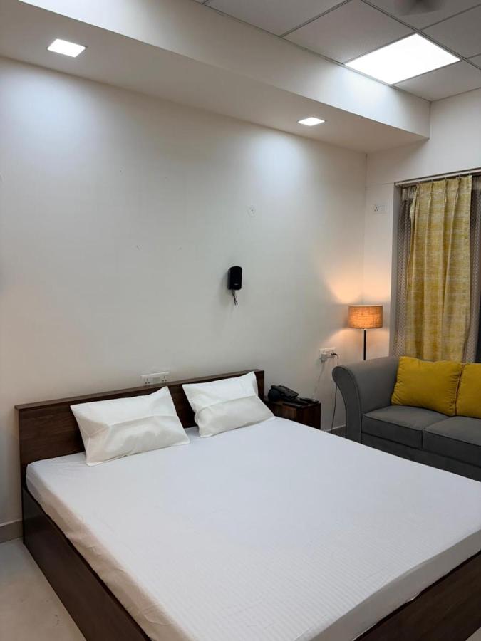 Deluxe studio double bed with white linen, a bedside phone, floor lamp and sofa by the window