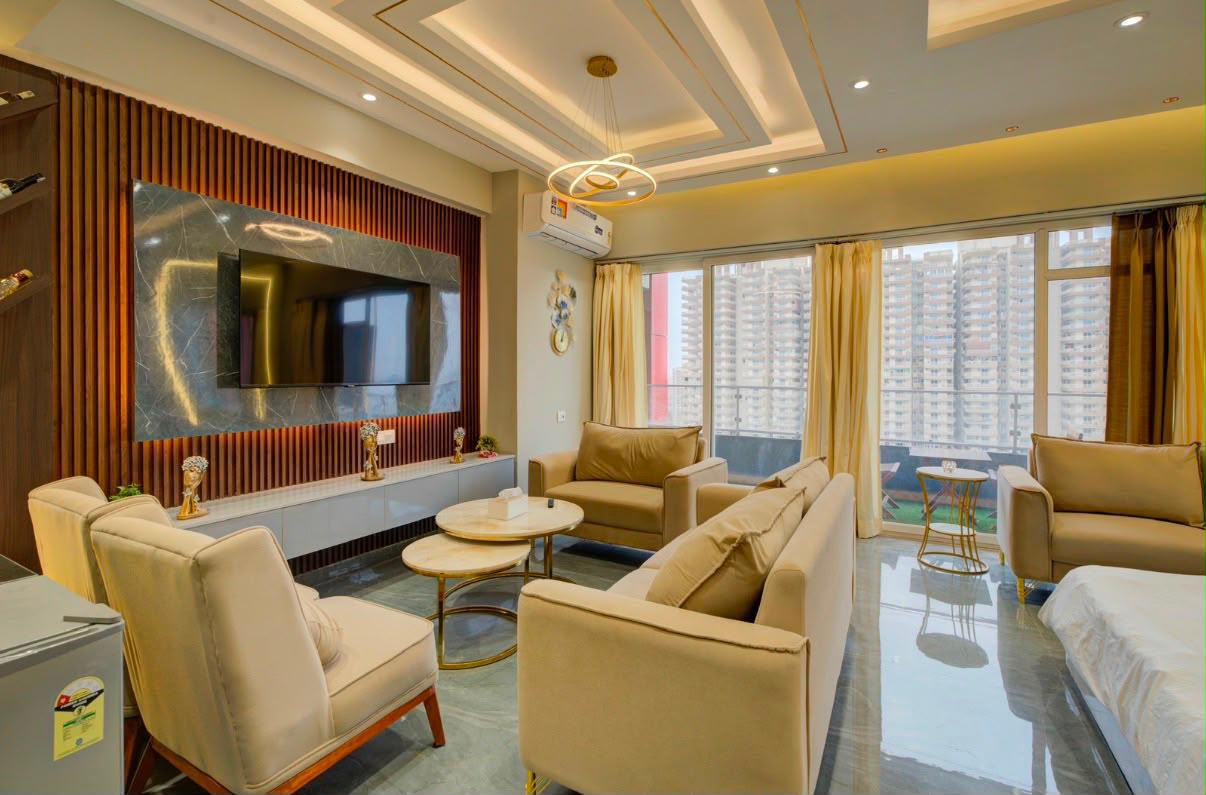 Studio living room with armchairs and a sofa in front of floor-to-ceiling windows opening onto a balcony